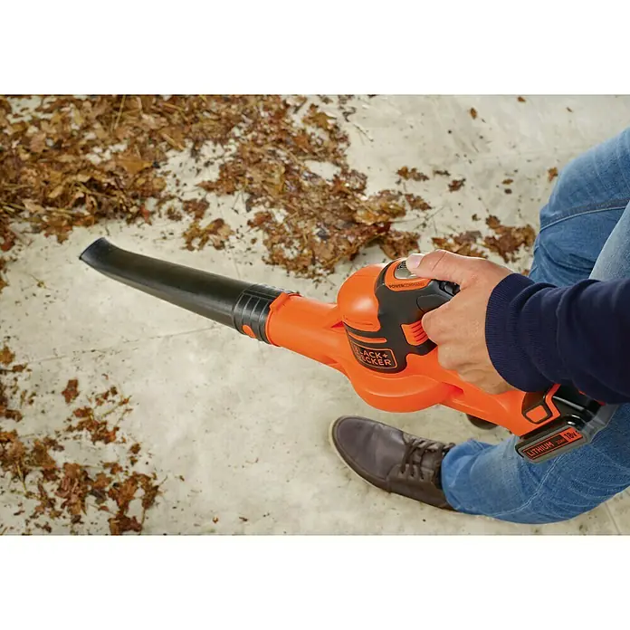 Black+Decker Soplador de hojas de batería Boost - 18 V, 2 Ah, Velocidad de soplado: 209 km/h, Potencia de soplado: 1,5 m³/min - Un soplador de hojas inalámbrico Black+Decker se está utilizando para soplar las hojas de un patio. El soplador de hojas es naranja y negro y tiene una batería.