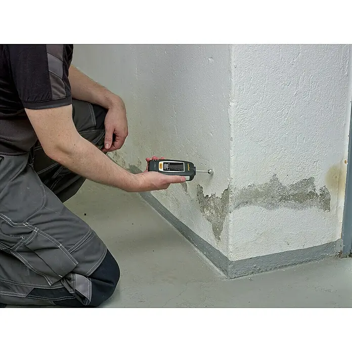 Laserliner Feuchtigkeitsmessgerät - Mit Batterien - Feuchtigkeitsmessgerät im Einsatz: Ein Mann prüft mit einem Messgerät die Feuchtigkeit an einer Wand im Innenbereich, um mögliche Schäden zu erkennen.