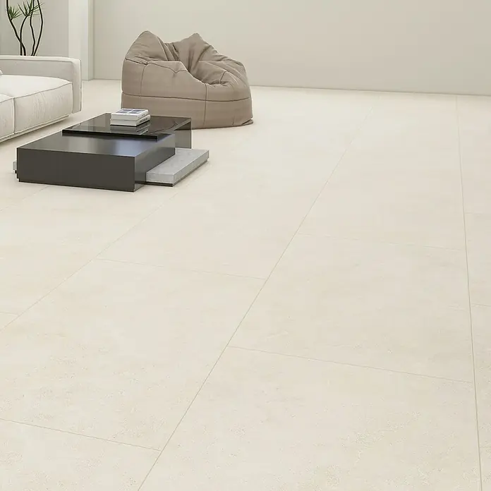 Vinylbodenmuster Rigid Fliese Palma - 297 x 180 x 5,5 mm, Steinoptik - Bild mit Fliesenboden in einem Wohnzimmer. Helle Fliesen erstrecken sich über den Raum mit Sofa, Tisch und Sitzsack im Hintergrund.