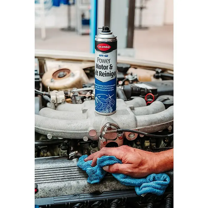 Caramba Motor- & Maschinenreiniger - 400 ml - Caramba Power Motor- und Alt Reiniger auf einem Motorblock, während eine Hand mit einem blauen Tuch wischt.