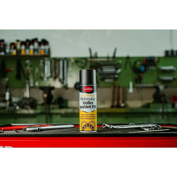 Caramba Mehrzweckfett Performance - 250 ml - Caramba Performance Weißes Sprühfett PTFE vor Werkstatthintergrund, ideal für anhaltenden Korrosionsschutz und hohe Temperaturen bis 250°C.