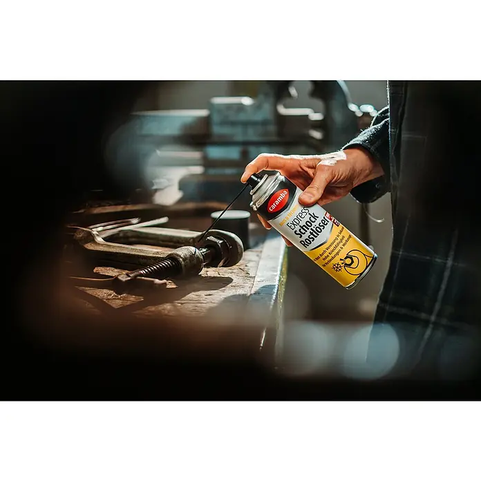 Caramba Rostlöser Express - 250 ml - Eine Dose Caramba Express Schock Rostlöser wird auf eine Werkbank mit Werkzeugen aufgesprüht.