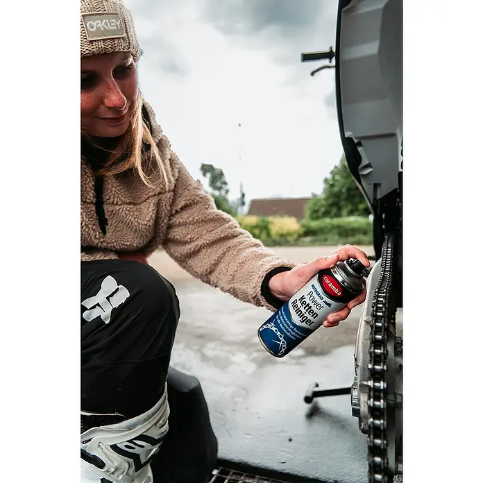 Caramba Kettenreiniger - 300 ml - Frau sprüht Caramba Power Ketten Reiniger auf eine Motorradkette.