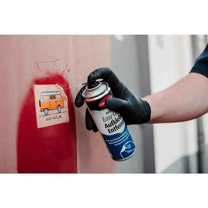 Caramba Kleberentferner Easy Clean - 300 ml - Eine Hand mit schwarzem Handschuh sprüht Auto Easy Clean Aufkleberentferner auf einen Aufkleber mit einem VW-Bus.