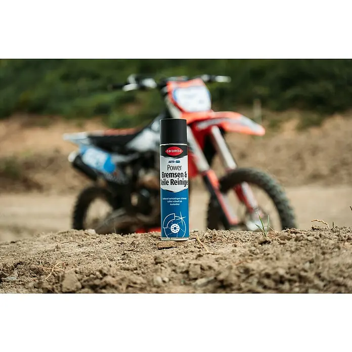 Caramba Bremsen- & Teilereiniger - 400 ml - Caramba Power Bremsen & Teile Reiniger steht vor einem Motocross-Bike. Das Spray sorgt für saubere und funktionstüchtige Bremsen und Teile.
