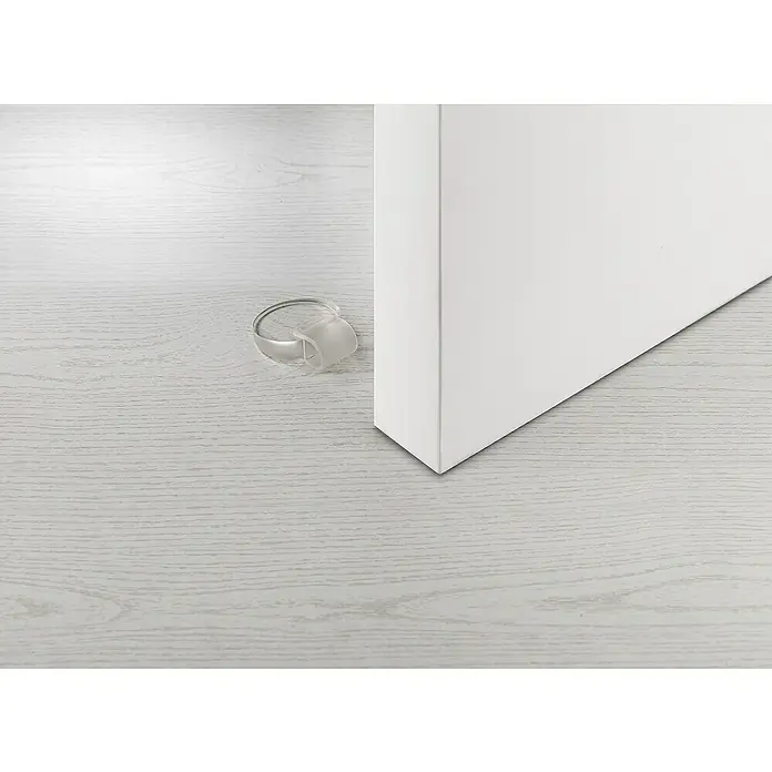 Inofix Tope de puerta 2054 - Caucho macizo, Transparente - Esta imagen muestra un tope de puerta transparente con forma de anillo colocado en un suelo de madera clara junto a una puerta blanca. Un accesorio práctico para el hogar.