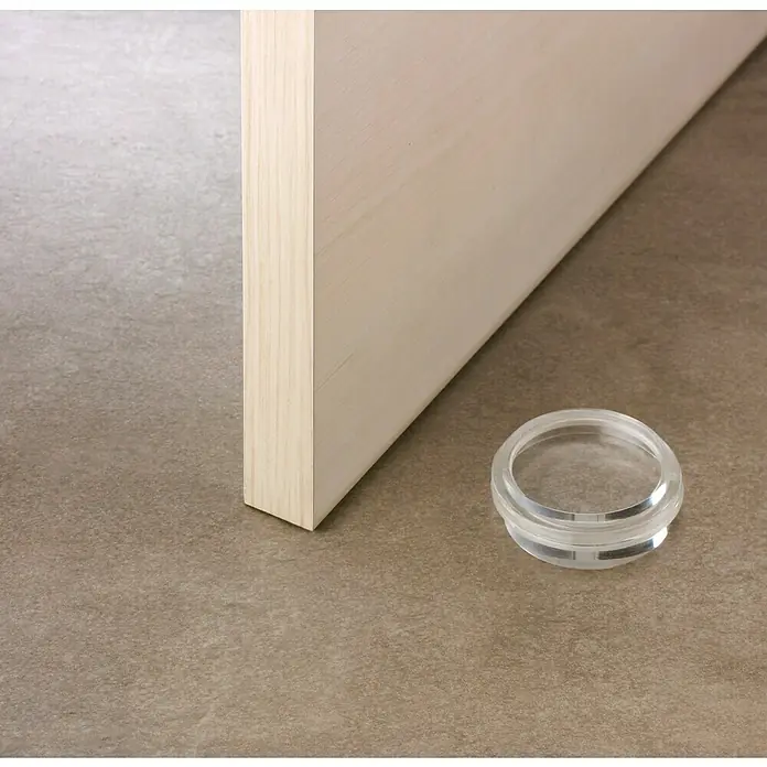 Inofix Tope de puerta 2054 - Caucho macizo, Transparente - Primer plano de una instalación de tope de puerta transparente en el suelo junto a una puerta de madera, combinando funcionalidad con diseño discreto.