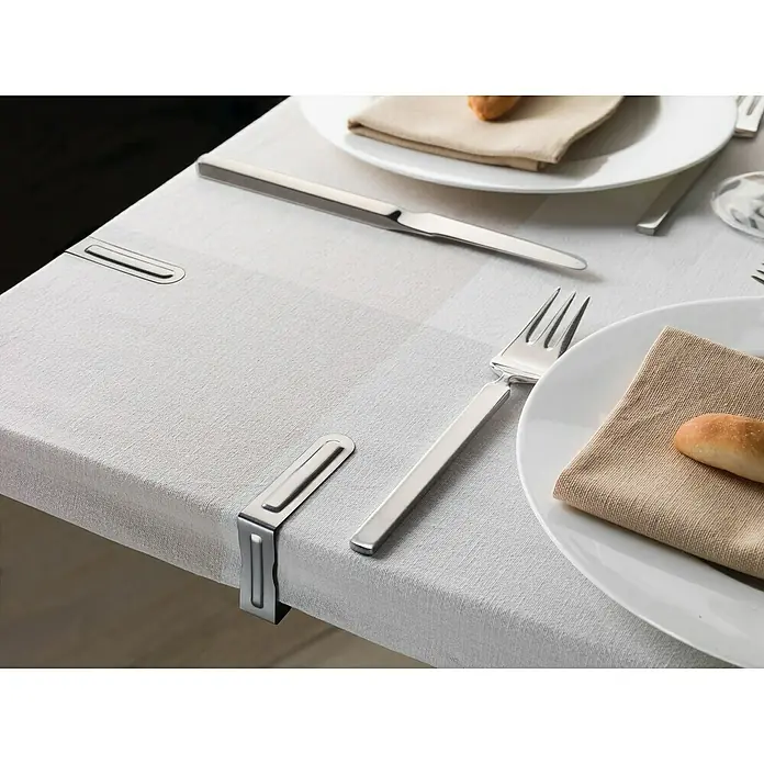 Inofix Pinza sujetamanteles - 4 ud., Acero inoxidable - Primer plano de una mesa puesta con mantel, platos, cubiertos y panecillos. Los clips para mantel se utilizan para fijar la tela, evitando que se deslice.