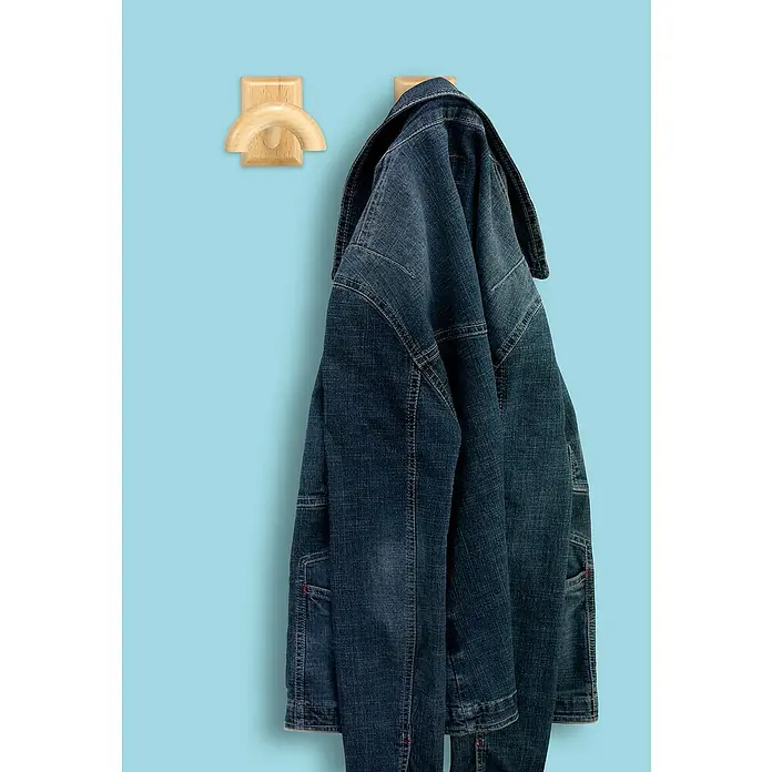 Inofix Colgador adhesivo Haya - Madera, Natural - Una chaqueta vaquera azul colgada de un perchero de pared de madera sobre un fondo azul claro.
