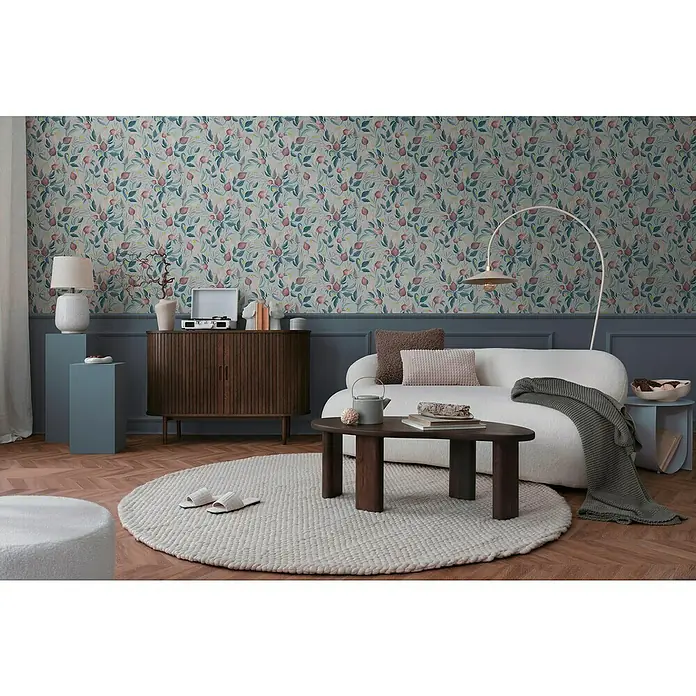 A.S. Création Cosmoliving by Cosmopolitan Vliestapete Blüte - Blau-Rosa-Pink, Floral, 10,05 x 0,53 m - Ein stilvolles Wohnzimmer mit einem beigen Sofa, einem dunklen Holztisch und einem gemusterten Hintergrund, der eine gemütliche Atmosphäre schafft.