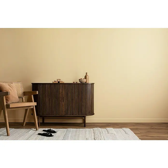 swingcolor Wandfarbe Comfort Home - Earth Dust, Stumpfmatt, 2,5 l, Konservierungsmittelfrei - Elegantes Interieur mit einem dunklen Holzschrank, einem hellen Holzstuhl und einem gemusterten Teppich auf einem Holzboden.