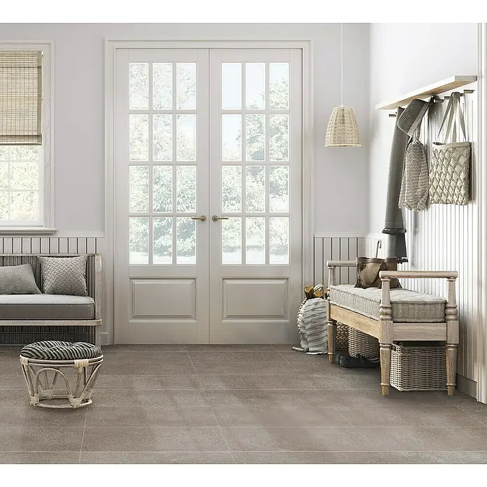 Feinsteinzeugfliese Rimini - 30,5 x 61 cm, Taupe, Matt - Ein einladender Flur mit grauen Bodenfliesen, einer Sitzbank und einer weißen Doppeltür, die ein helles und freundliches Ambiente schafft.