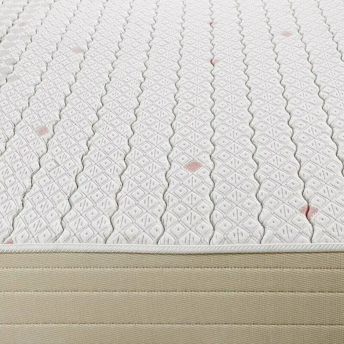Espacio Descanso Colchón - Largo: 190 cm, Ancho: 135 cm, Altura: 22 cm, Espuma HR y Viscoelástica, Colchón a 2 caras - Primer plano de un colchón con una funda acolchada con detalles en rosa. El colchón tiene una base beige y un patrón texturizado.