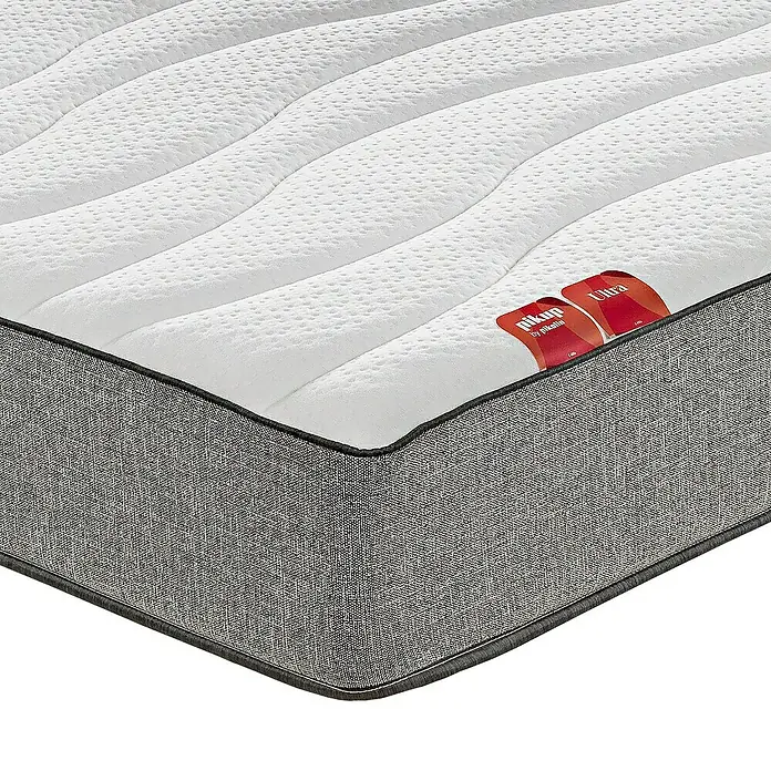 Pikolin Colchón PikUp Ultra - Largo: 190 cm, Ancho: 150 cm, Altura: 26 cm, Espuma HR y Viscoelástica, Se entrega enrollado - Primer plano de un colchón con una parte superior acolchada blanca y un borde gris. La etiqueta "Niku Up Ultra" es visible.