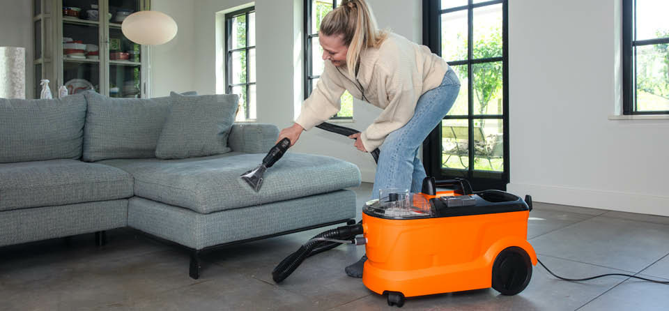 Eine Frau saugt mit dem Boels Teppichreniger die Couch ab 