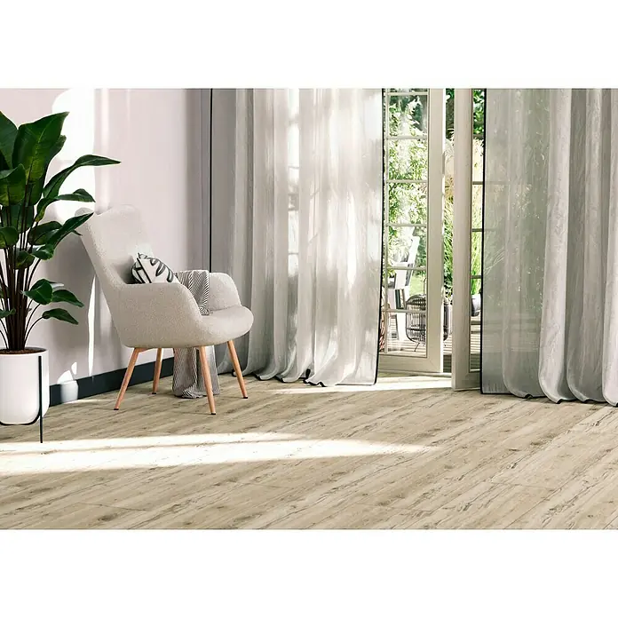Feinsteinzeugfliese Essenza - 30 x 120 cm, Bianco, Matt - Elegantes Interieur mit hellem Holzfußboden, einem bequemen Sessel und luftigen, weißen Vorhängen, die eine entspannende Atmosphäre schaffen.
