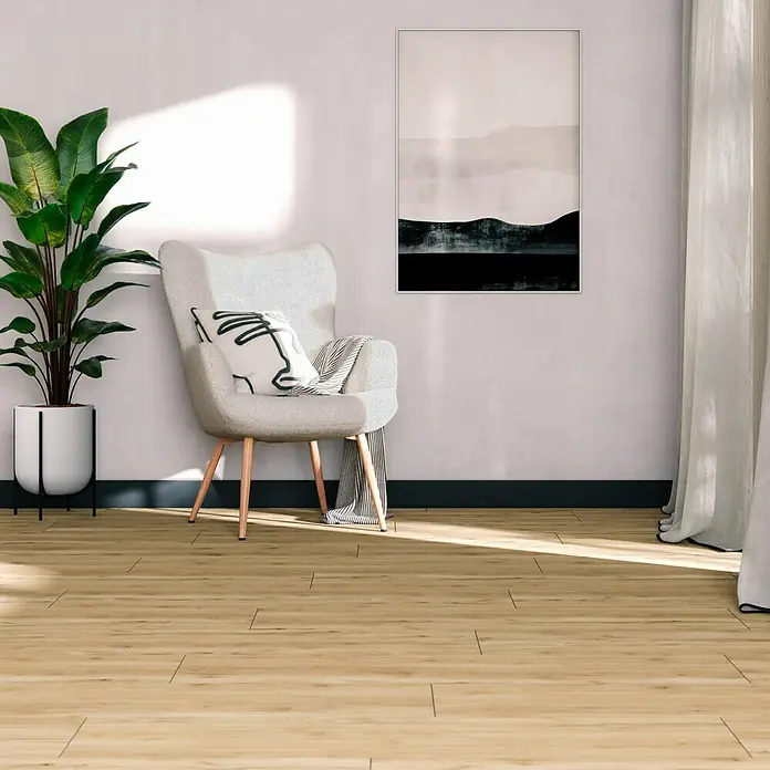 Feinsteinzeugfliese Essenza - 20 x 120 cm, Caldo, Matt - Elegantes Interieur mit einem hellgrauen Sessel, einer Zimmerpflanze und einem modernen Gemälde an einer schlichten Wand.