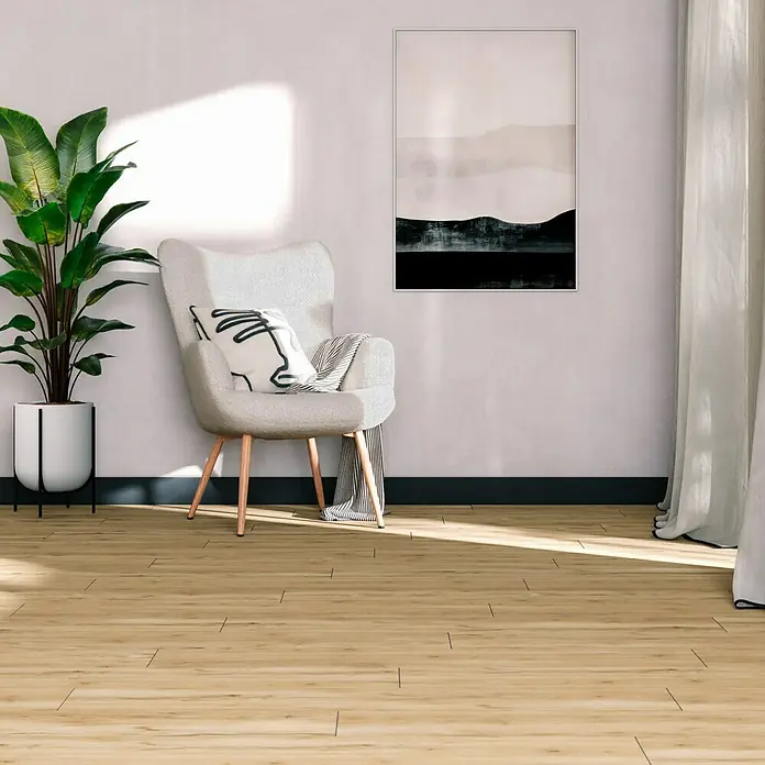 Feinsteinzeugfliese Essenza - 30 x 120 cm, Caldo, Matt - Einladender Wohnraum mit einem bequemen Sessel mit Kissen, einer Zimmerpflanze und einem eleganten Bild an der Wand. Helle Holzböden vervollständigen den Look.