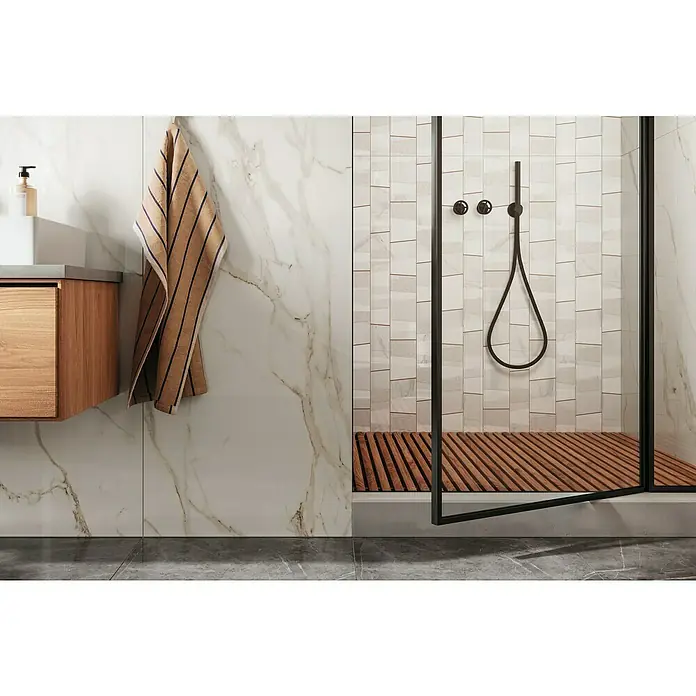 Atlas Concorde Solution Marble Vison Feinsteinzeugfliese Calacatta Caldo - 60 x 120 cm, Weiß, Glänzend - Badezimmer mit einem Waschtischunterschrank aus Holz, einem gestreiften Handtuch und einer Dusche mit Holzboden und schwarzem Duschkopf.