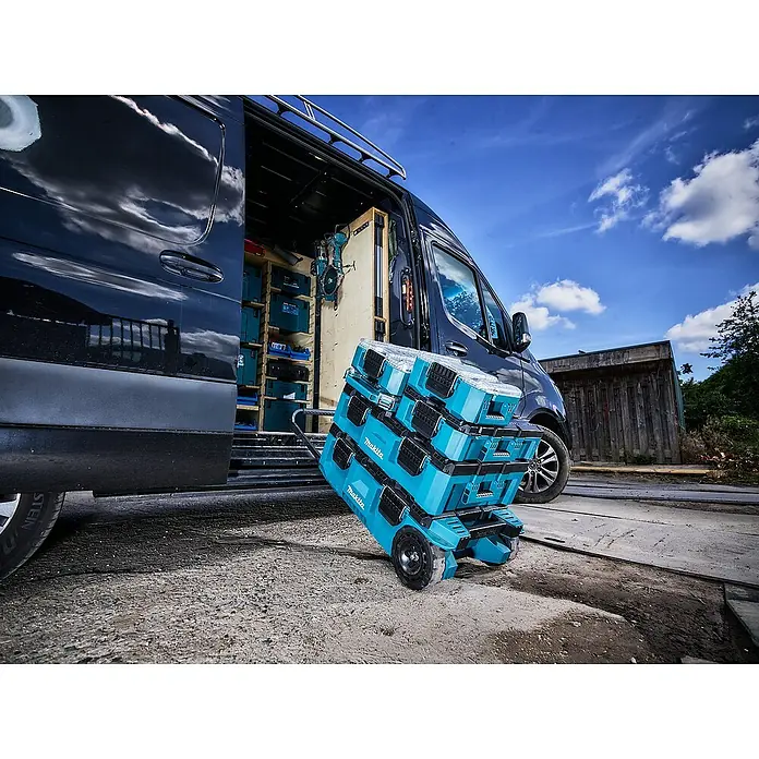 Makita Organizer Maktrak Flach L - L x B x H: 59,6 x 38,7 x 8,5 cm, Anzahl Fächer: 11 Stk. - Der blaue Makita Werkzeugwagen mit mehreren Boxen vor einem Transporter präsentiert die ideale mobile Werkzeugaufbewahrung für Handwerker.