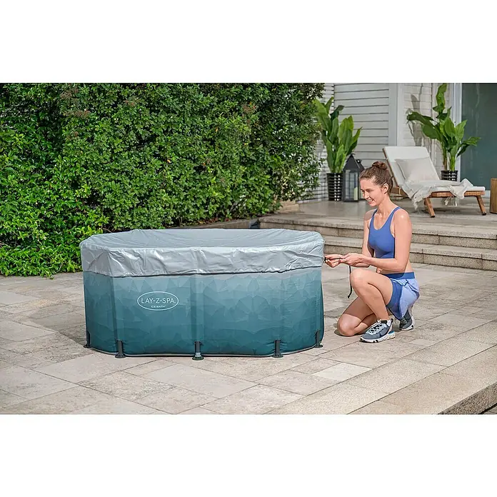 Bestway Lay-Z-Spa Eisbad Glacial Dip - L x B x H: 152 x 92 x 71 cm - Eine Frau sichert die Abdeckung eines Lay-Z-Spa Ice Bath Whirlpools im Freien.