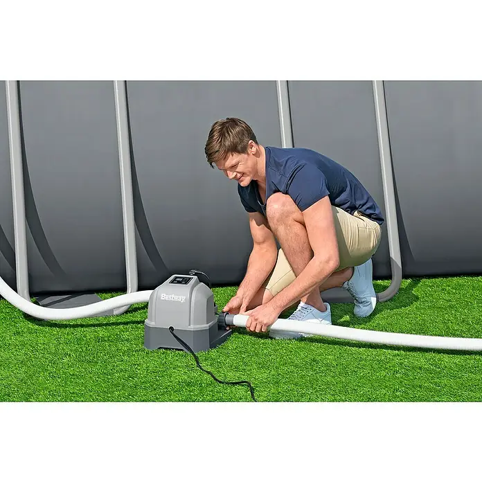 Bestway Salzwassersystem Hydrogenic - Passend für: Filtersysteme ab 1.249 l/h Leistung, Benötigte Start-Salzmenge: 3 g/l - Mann schließt eine Bestway-Poolheizpumpe an einen Pool an. Sie sorgt für eine angenehme Wassertemperatur und Badespaß.