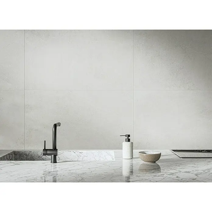 Feinsteinzeugfliese Cloudstone - 59,7 x 59,7 cm, Pearl, Matt - Nahaufnahme einer modernen Küchenarmatur aus dunklem Metall auf einer Marmorarbeitsplatte, daneben Spülmittel und eine Schale.