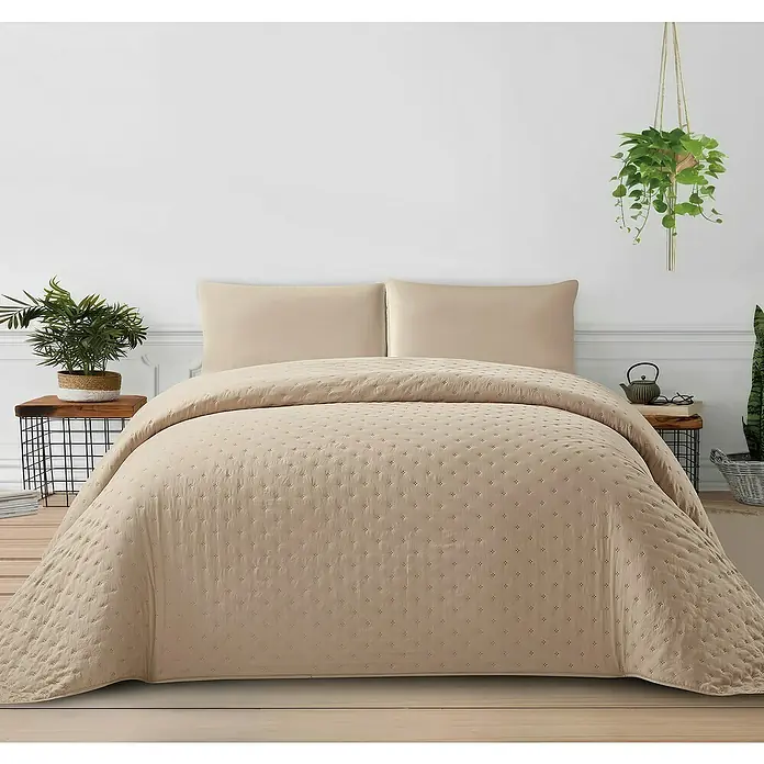 Edredón Corinto - 180 x 260 cm, Poliéster, Taupe - Primer plano de un conjunto de colcha acolchada beige sobre una cama con mesitas de noche y plantas.