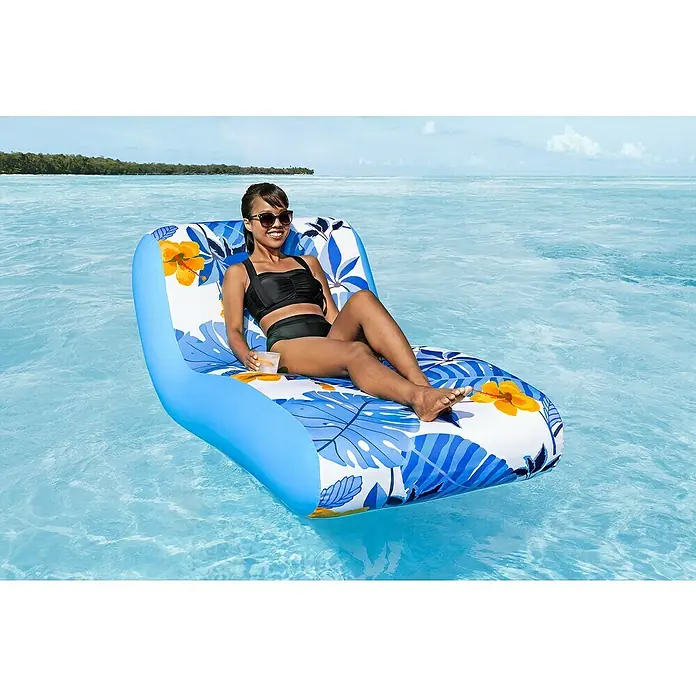 Bestway Luftmatratze Blissfull Drifter - Länge: 155 cm, Breite: 96 cm - Frau entspannt auf einer aufblasbaren Sonnenliege mit tropischem Muster auf dem türkisfarbenen Wasser, ein erfrischendes Getränk in der Hand.