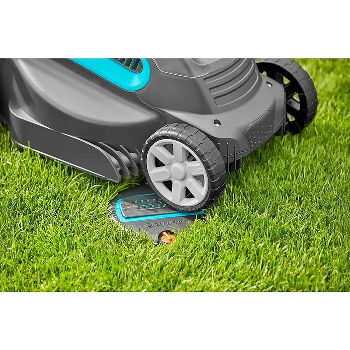 Gardena Sprinklersystem Viereckregner OS 140 Komplettset - Max. Regnerfläche: 140 m², 10 -tlg. - Nahaufnahme eines Gardena Mähroboters, der auf einer Ladestation auf grünem Rasen steht.