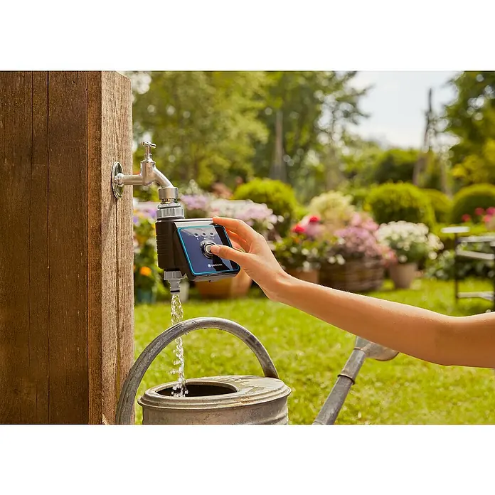 Gardena Bewässerungscomputer Bluetooth - Bewässerungsdauer: 1 min - 480 min - Eine Hand bedient den Gardena Wasserhahn-Steuerung, während sie einen Eimer mit Wasser füllt, um einen schönen Garten zu bewässern.