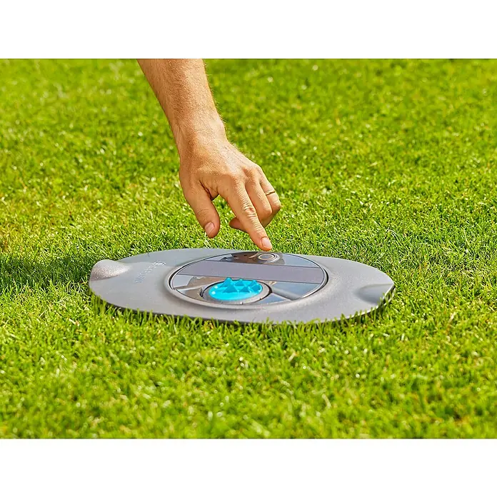 Gardena Sprinklersystem Versenkregner-Set AquaPrecise Basis - Max. Regnerfläche: 320 m², Reichweite ca.: 2 m - 10 m - Ein Mann aktiviert einen Gardena Rasensprenger auf einem grünen Rasen. Praktische Bewässerung für den Garten.