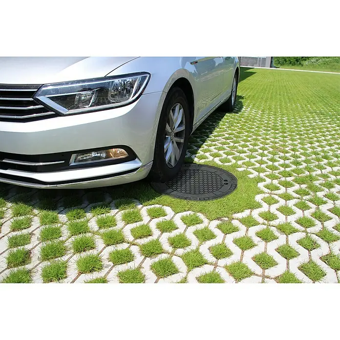 Garantia Tankdeckel PKW-Modul - Durchmesser: 725 mm, Geeignet für: Regenwassernutzungsanlagen - Rasenpflastersteine mit einem Gullydeckel auf einer Grünfläche, auf der ein silbernes Auto geparkt ist.