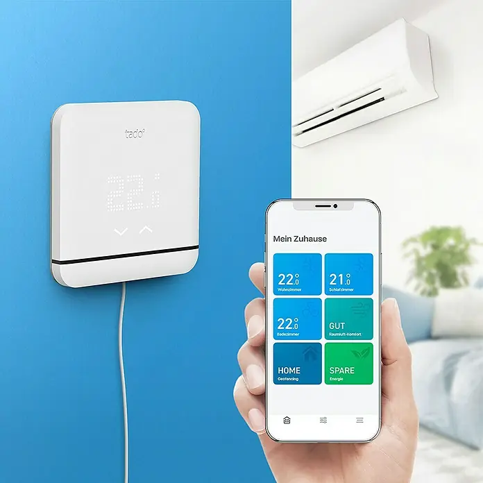 Tado Control de aire acondicionado - Control inteligente: App Tado - Sistema de termostato inteligente con termostato tado° en la pared y aplicación móvil en mano.