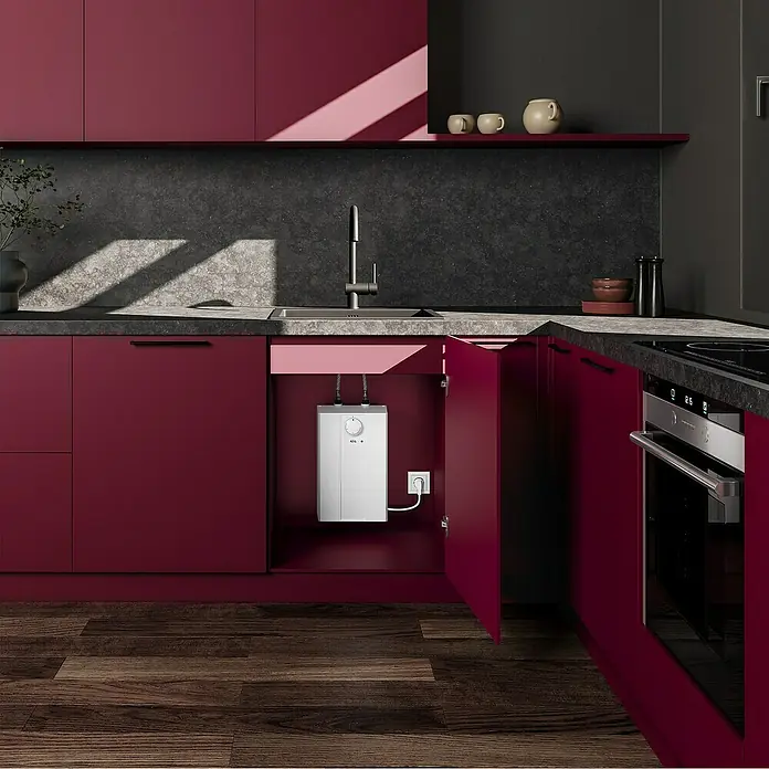 AEG Termo eléctrico Huz 5 Basis - 5 l, 2.000 W, Rango de temperaturas: 35 °C - 85 °C, Montaje bajo mesa - Un calentador de agua compacto AEG instalado en un armario de cocina rojo debajo del fregadero, asegurando suministro de agua caliente instantáneo.