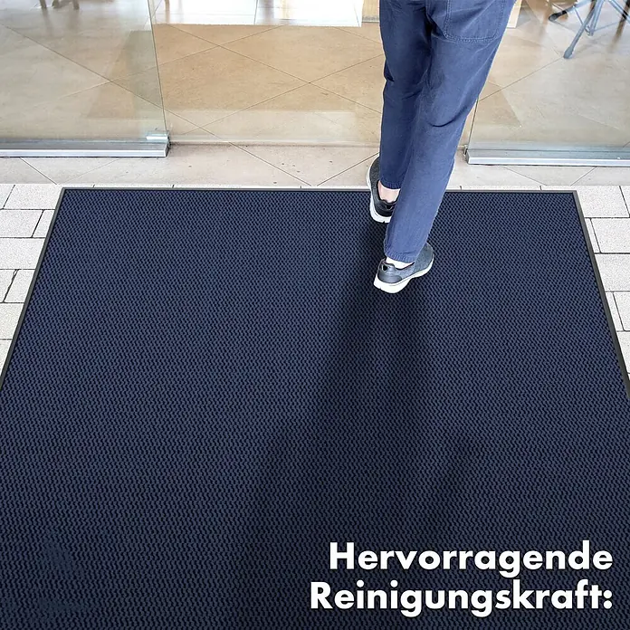 Fußmatte Sky Novo - Blau, 60 x 40 cm, 100 % Polypropylen - Eine blaue Fussmatte vor einer Glastür mit einer Person, die darauf steht. Hervorragende Reinigungskraft!