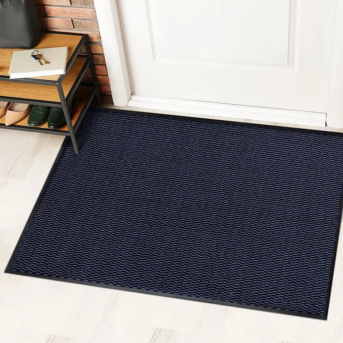 Fußmatte Sky Novo - Blau, 60 x 40 cm, 100 % Polypropylen - Eine dunkelblaue Fußmatte mit OEKO-TEX-Zertifikat vor einer weißen Tür und einem Schuhregal.