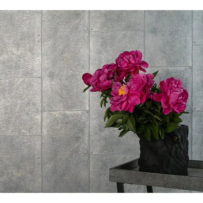 Marburg Loft Vliestapete Fliesenoptik - Silber, Fliesenoptik, 10,05 x 0,53 m - Nahaufnahme eines dekorativen schwarzen Löwengefäßes mit prächtigen rosa Pfingstrosen auf einem stilvollen Beistelltisch vor einer grauen Wand.