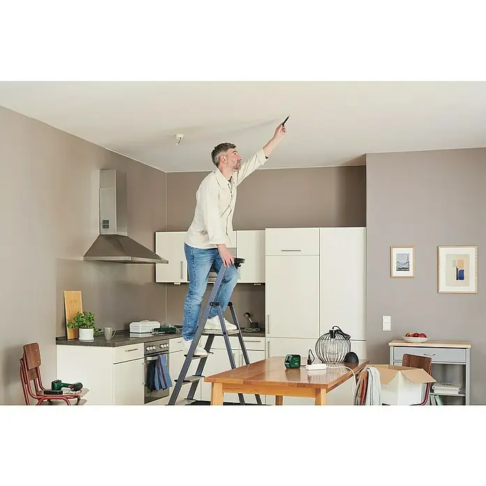 Bosch Kreuzlinienlaser Advanced Level 2G - Max. Arbeitsbereich: 15 m - Mann auf einer Leiter, der die Decke überprüft, wahrscheinlich um Reparaturen oder Installationen vorzubereiten.