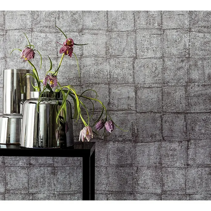 Marburg Casual Vliestapete Karomuster - Braun/Grau, Grafisch, 10,05 x 0,53 m - Dekoratives Stillleben mit einer Vase mit Blumen auf einem Tisch, vor einer grauen Wandtapete mit quadratischem Muster.