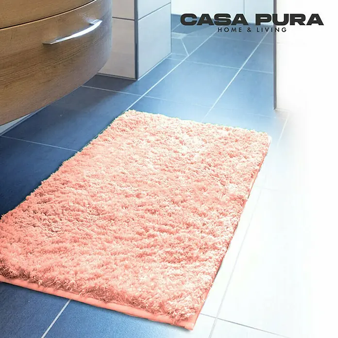 Floordirekt Badteppich Sky - 150 x 80 cm, Rosa, 100% Polyester - Ein rechteckiger, rosa Casa Pura Badteppich mit langen Fasern liegt auf blau gefliestem Boden in einem Badezimmer.