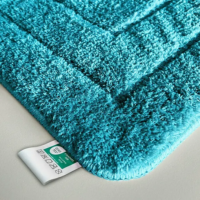 Floordirekt Badteppich Atlantis - 120 x 70 cm, Türkis, 100% Polyester - Nahaufnahme einer türkisfarbenen Badematte mit OEKO-TEX-Etikett, die weiche Textur und hochwertige Verarbeitung betont.