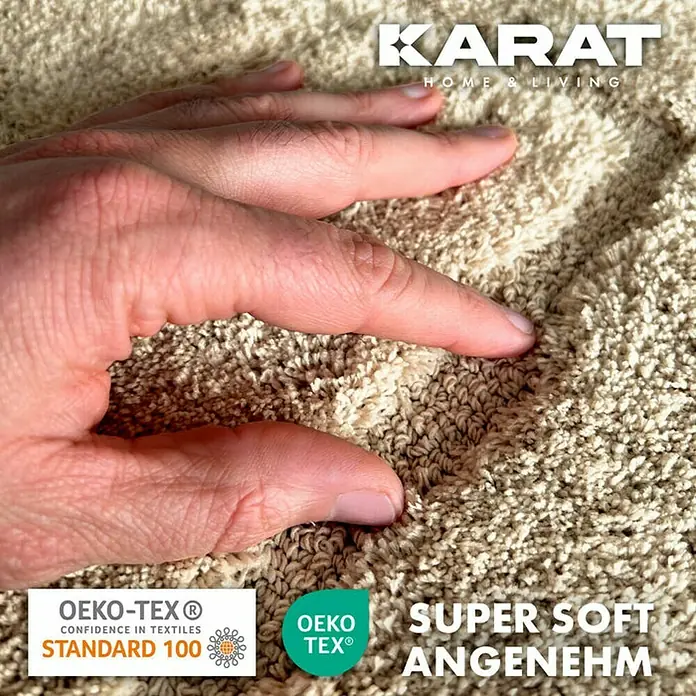 Floordirekt Badteppich Atlantis - 120 x 70 cm, Beige, 100% Polyester - Nahaufnahme eines beigen Karat Home & Living Teppichs mit der Hand, der seine superweiche Textur und sein angenehmes Gefühl zeigt.