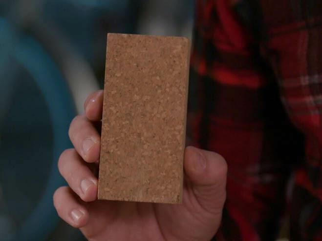 Mann hält Schleifblock aus Kork in der Hand