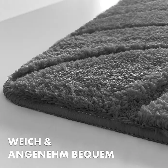 Floordirekt Badteppich Maris - 60 x 40 cm, Dunkelgrau, 100% Polyester - Detailaufnahme einer weichen, grauen Badematte mit gerippter Textur und umsäumten Kanten, die Komfort und Qualität verspricht.