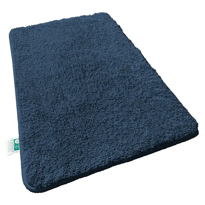 Floordirekt Badteppich Sky - 120 x 70 cm, Dunkelblau, 100% Polyester - Ein marineblauer, rechteckiger, flauschiger Badteppich liegt diagonal auf einer schwarzen Oberfläche und bietet Komfort und Stil für jedes Badezimmer.
