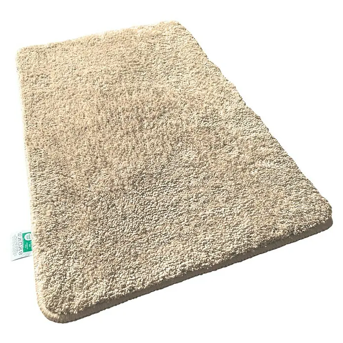 Floordirekt Badteppich Sky - 120 x 70 cm, Beige, 100% Polyester - Ein beiger, rechteckiger, flauschiger Teppich mit kurzem Flor, der auf einem glänzenden, schwarzen Untergrund liegt.