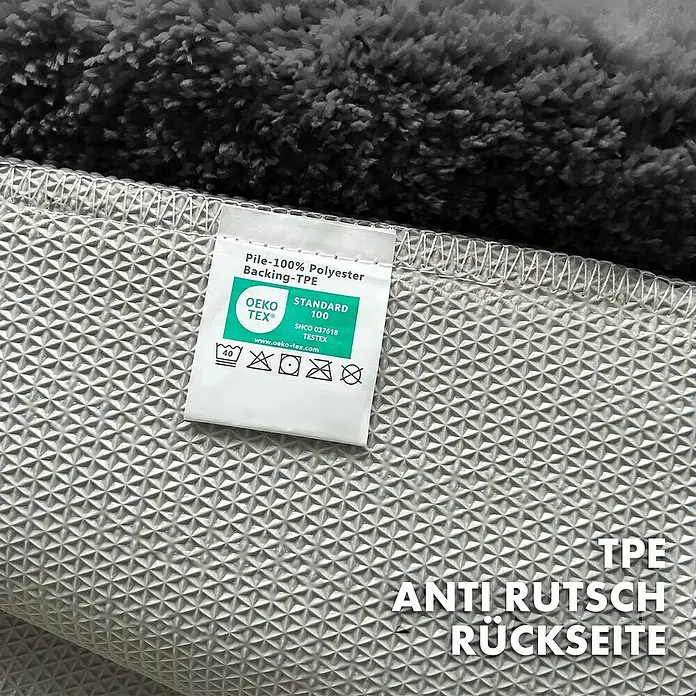 Floordirekt Badteppich Maris - 60 x 40 cm, Schwarz, 100% Polyester - Detailaufnahme eines Teppichs mit Etikett, das Materialinformationen und Pflegehinweise zeigt. Die rutschfeste TPE-Rückseite ist sichtbar.