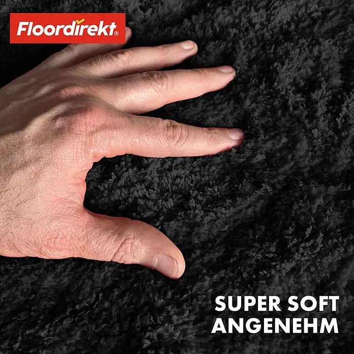 Floordirekt Badteppich Sky - 120 x 120 cm, Schwarz, 100% Polyester - Nahaufnahme eines schwarzen, superweichen Teppichs mit einer Hand, die seine Textur berührt. Zertifiziert durch OEKO-TEX.