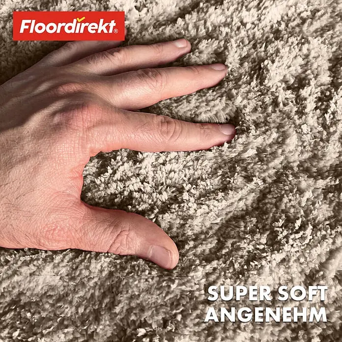 Floordirekt Badteppich Sky - 120 x 120 cm, Beige, 100% Polyester - Nahaufnahme eines flauschigen Floor direkt Teppichs mit einer Hand, die die weiche Textur berührt, zertifiziert mit dem Öko-Tex Standard.